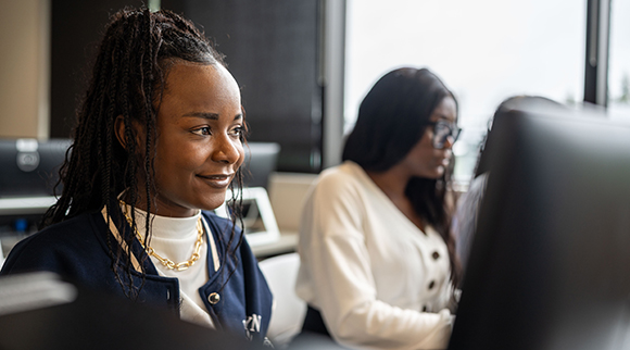 A student smiles to themselves while seated in BC's computer lab.
