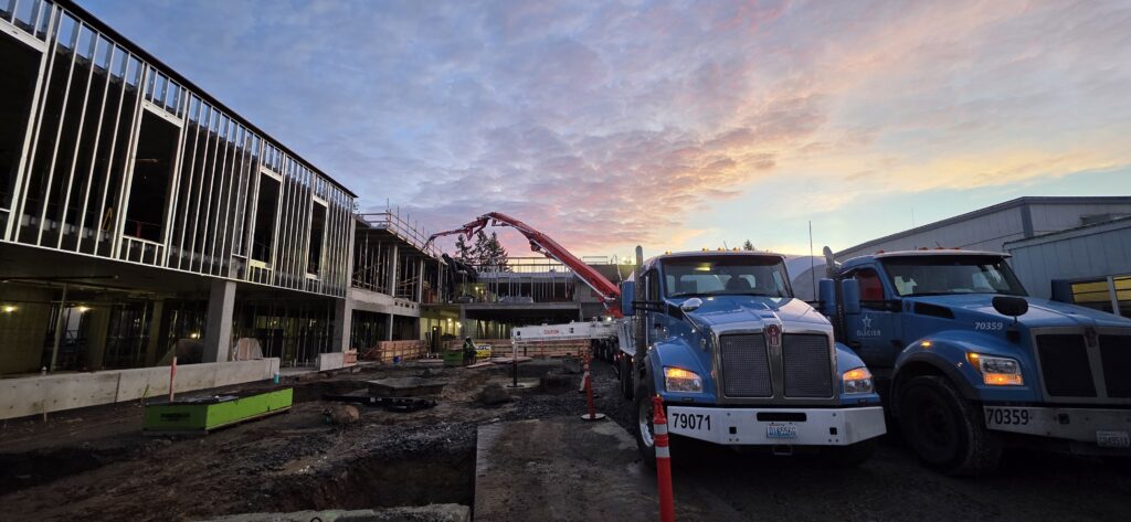 Two blue trucks with a red crane and the W Building under construction.