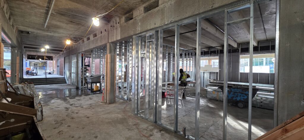Inside the building, there is a construction site with a cement beam and metal wall supports.