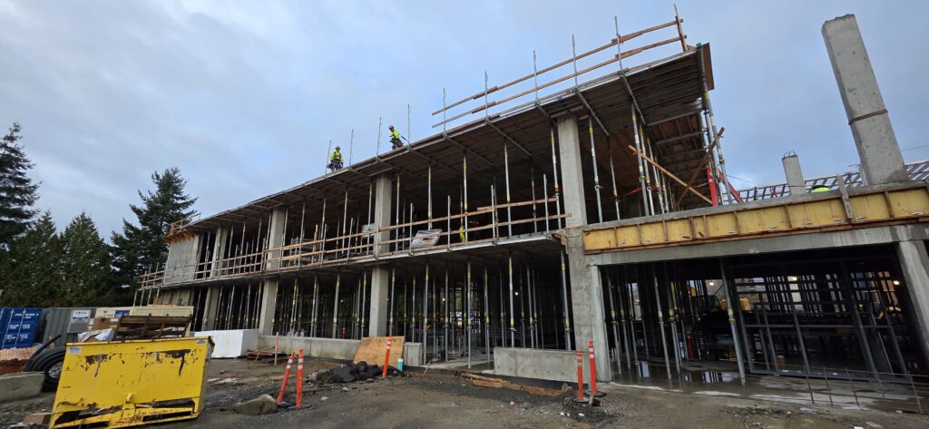 Side of building with two construction workers on roof.