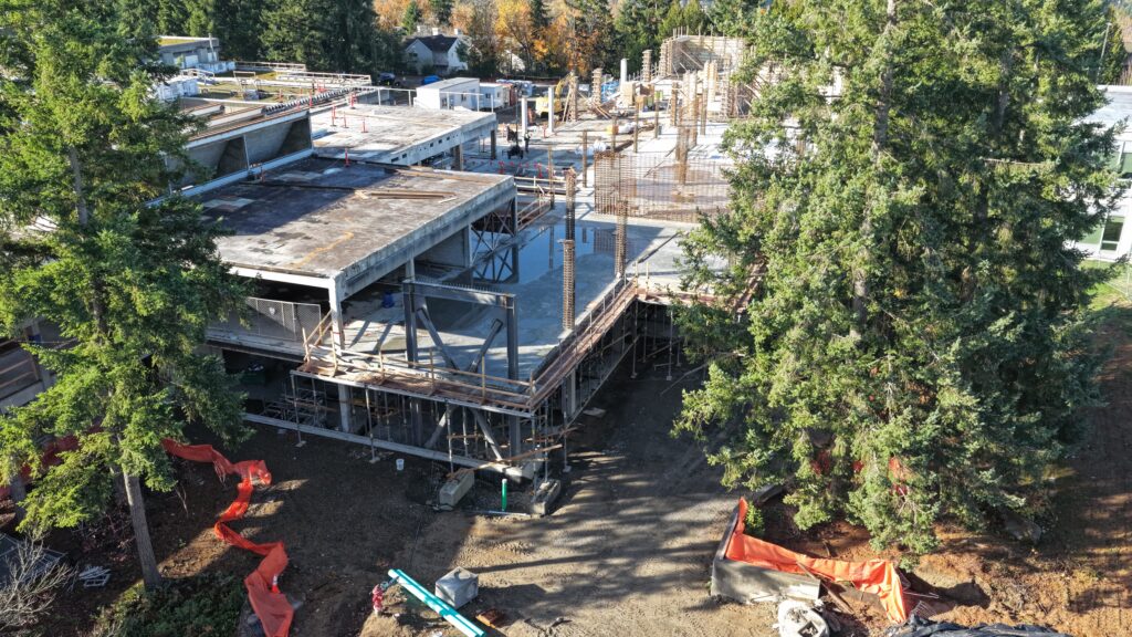 A view of a building under construction with trees framing it.