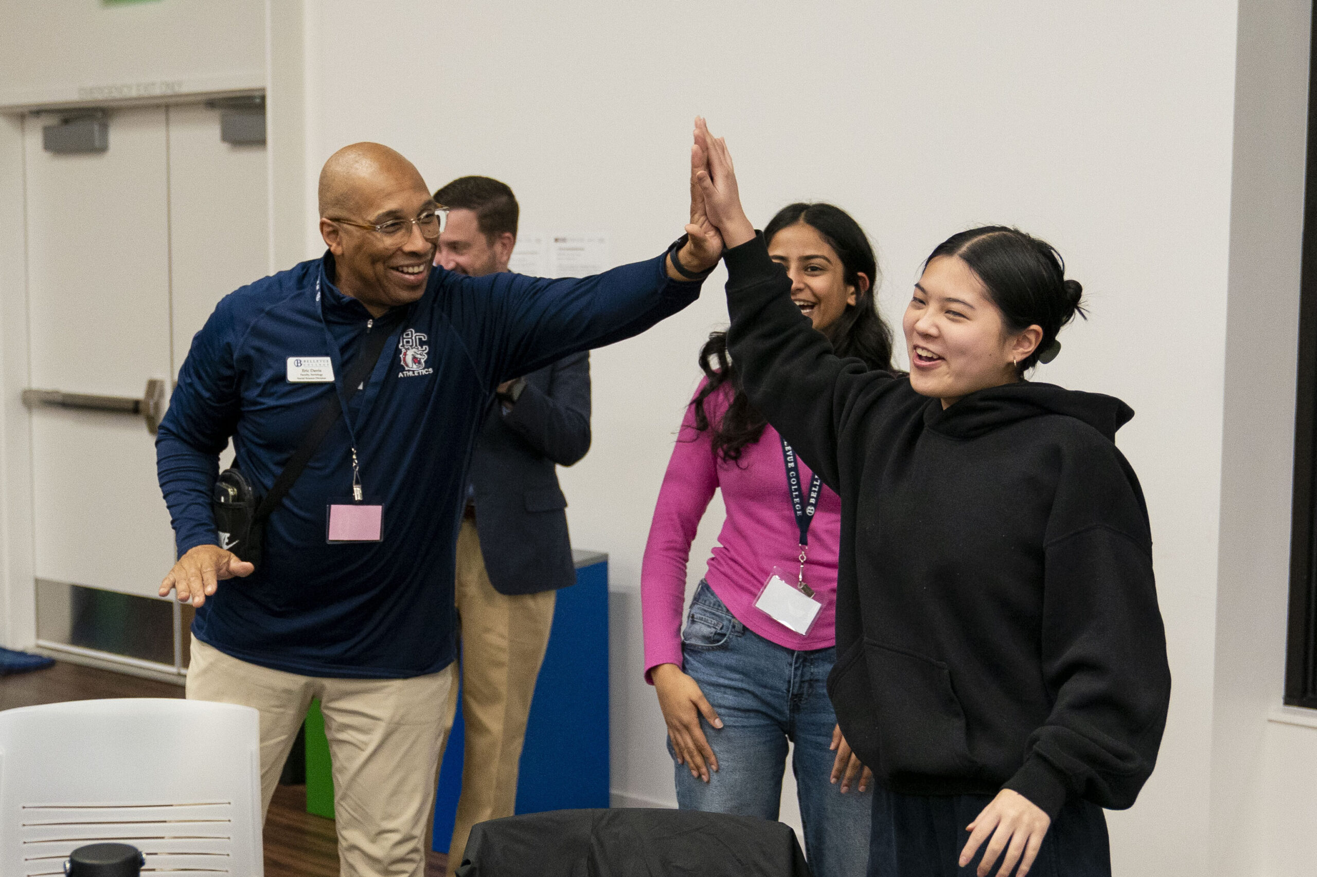 Two people high-five as they stand, smiling, with two other people behind them.