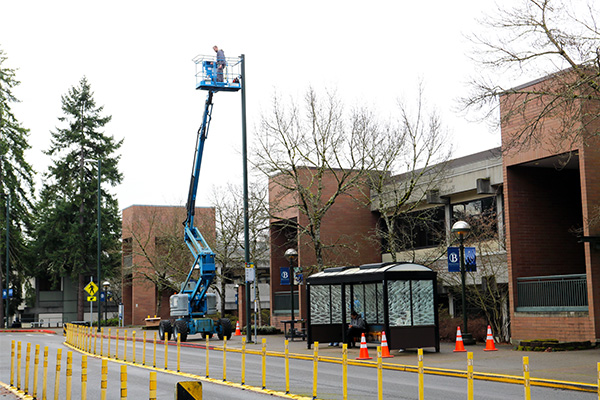 A person in a crane installs a street light on Bellevue College's campus.