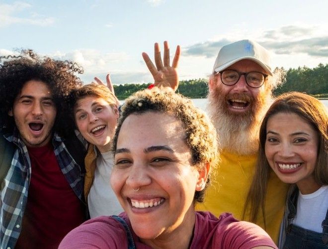 A woman in the foreground takes a selfie with three smiling friends in the background