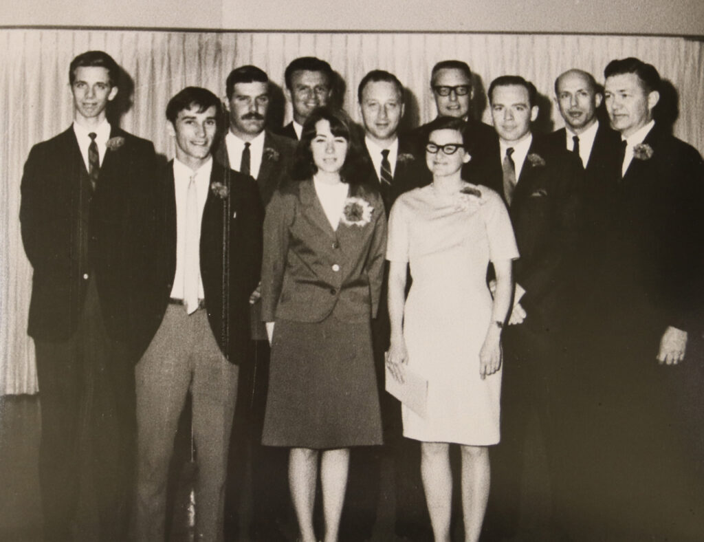 Group of 11 people stand smiling.