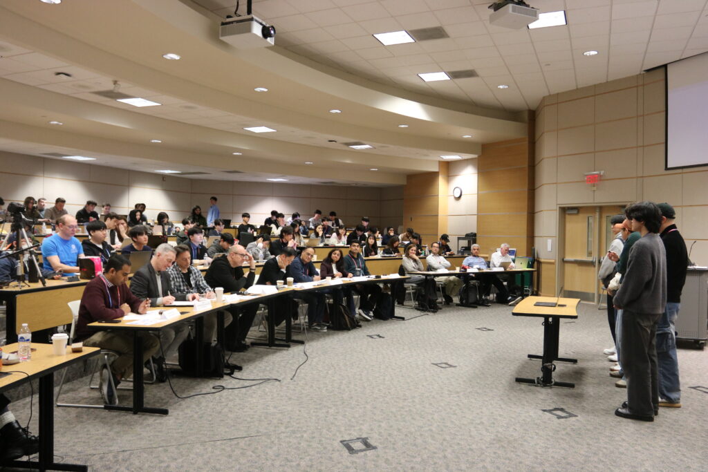 Group of people present a project in front of classroom full of people.