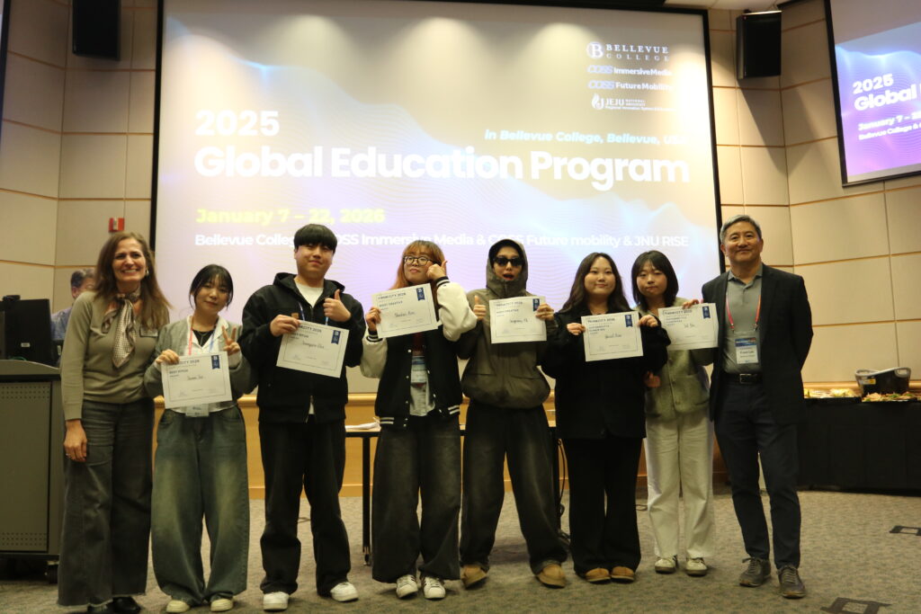Group of people stand as they hold up paper awards in front of classroom.