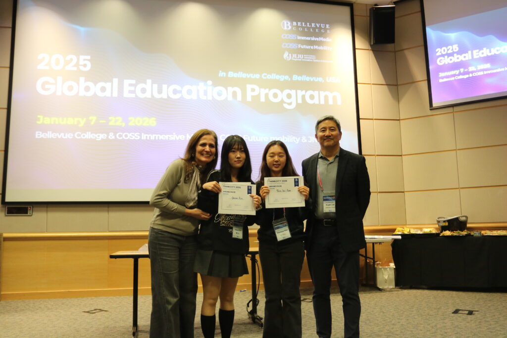 Four people stand, smiling, as two people hold up paper awards.