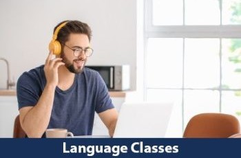 A smiling man wearing headphones looking at his laptop with a small bottom banner that says "Language Classes"