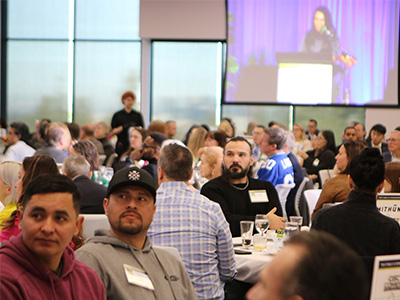 People sit at tables with a speaker in the background.