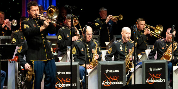Person plays saxophone in front of other people playing instruments.