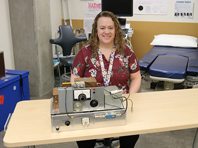Faculty member sitting with the Doppler ultrasound machine.