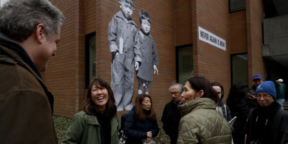 Seattle artist Erin Shigaki talks with people at Bellevue College in front of her “Never Again is Now” mural.
