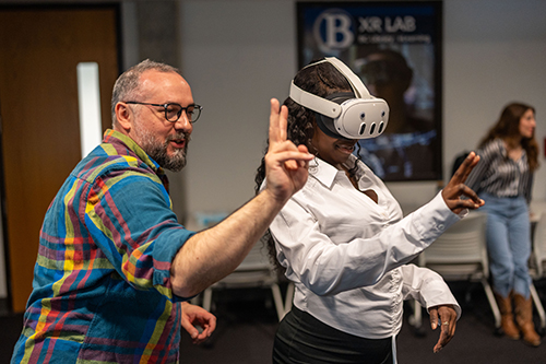 A student wearing a VR headset gets a demonstration from an instructor in how it works.