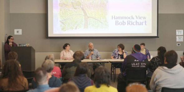 People sit in classroom with panelists at the front.