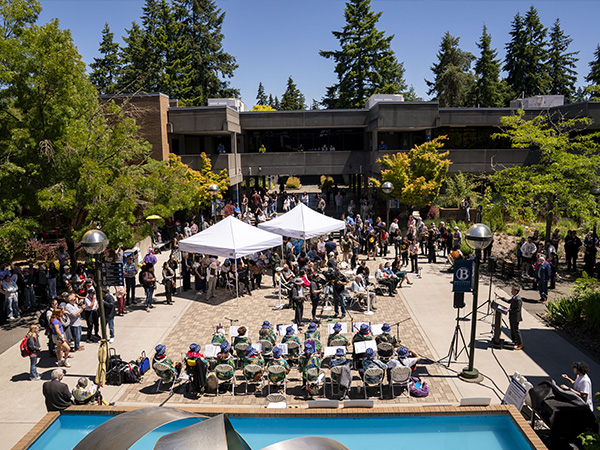 A large crowd at the Bellevue College Fountain Courtyard with two white tents.
