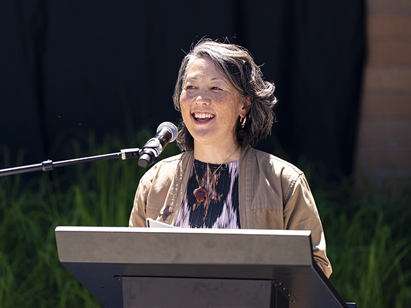 Artist Erin Shigaki speaks at a podium.
