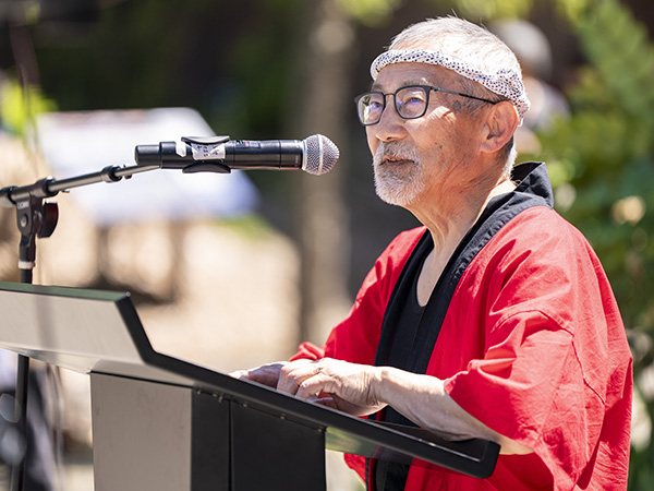 Advocate Stan Shikuma speaks at a podium.