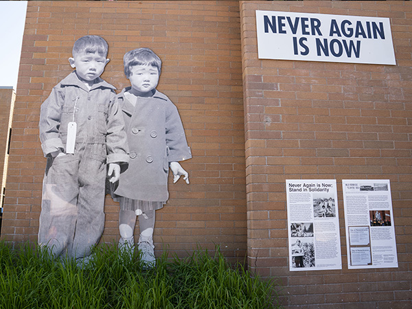The Never Again is Now mural depicting two Japanese American children with supporting text on a wall outside.