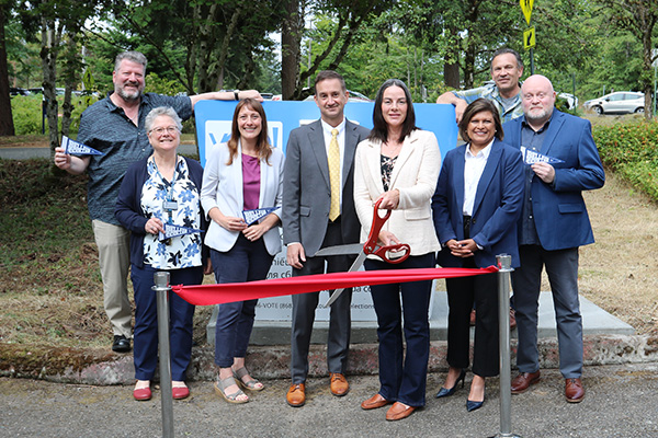 A person holds a pair of scissors at the ribbon-cutting for the new ballot drop box on campus.