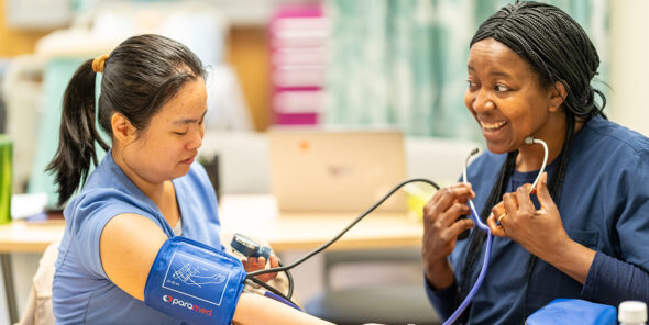 One student takes the blood pressure of another student.
