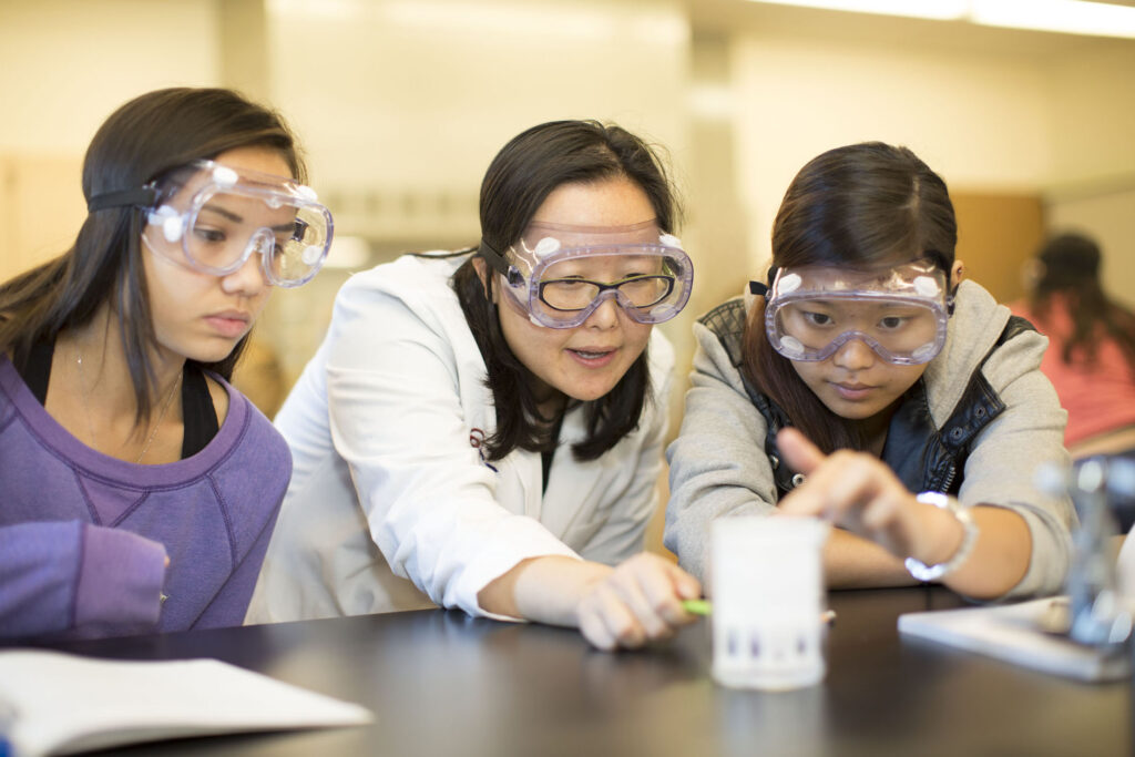 A professor gives hands-on instruction in a science lab.