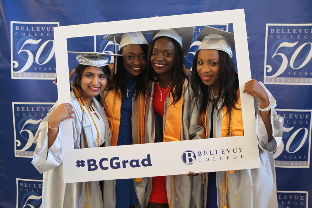 Four proud graduates pose together in caps and gowns.