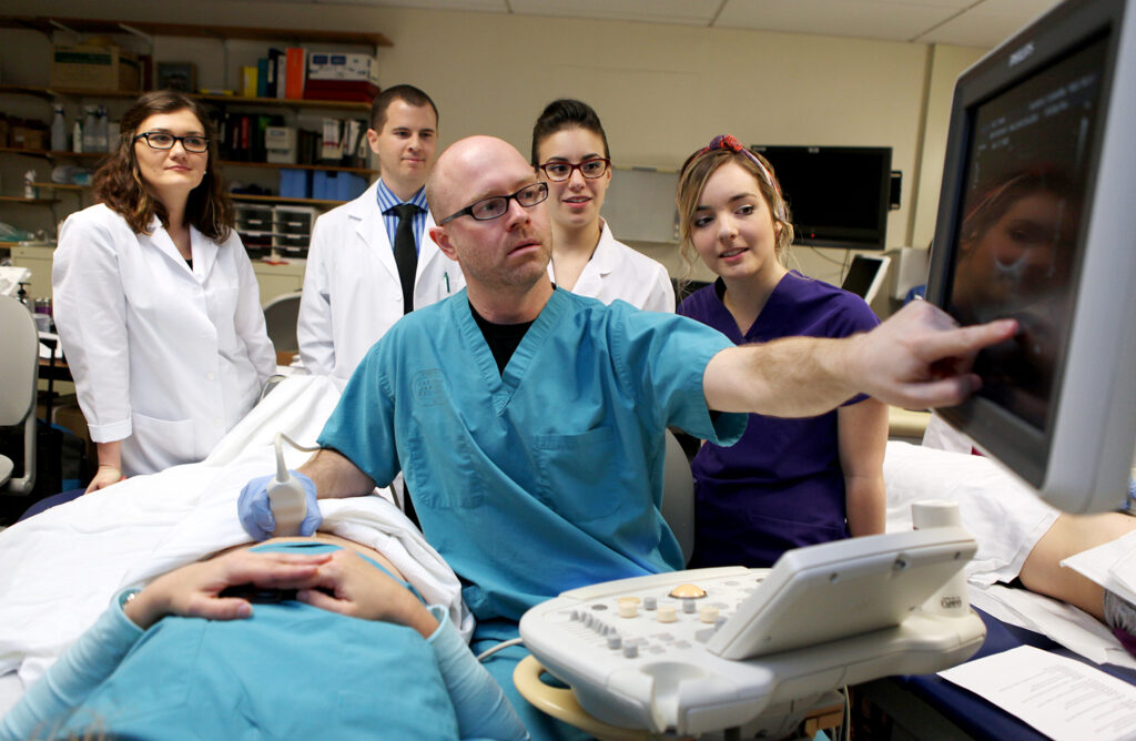 A professor demonstrates ultrasound imaging on a patient.