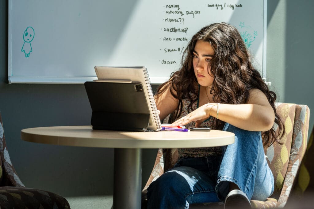 A student studies with a notebook and iPad.