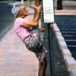 Elderly woman doing a leg split up a stop sign