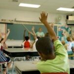 Kids raising their hands in a classroom