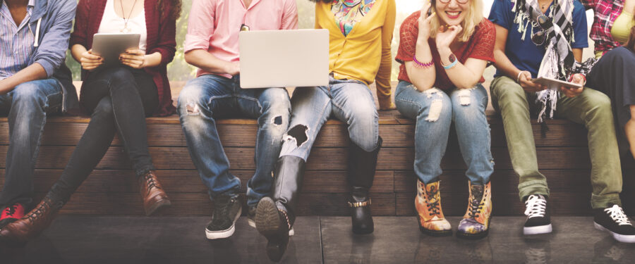 Students sitting along a wall only their legs are visible