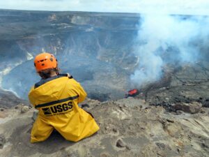 Scientist sitting on edge of volcanic crater.