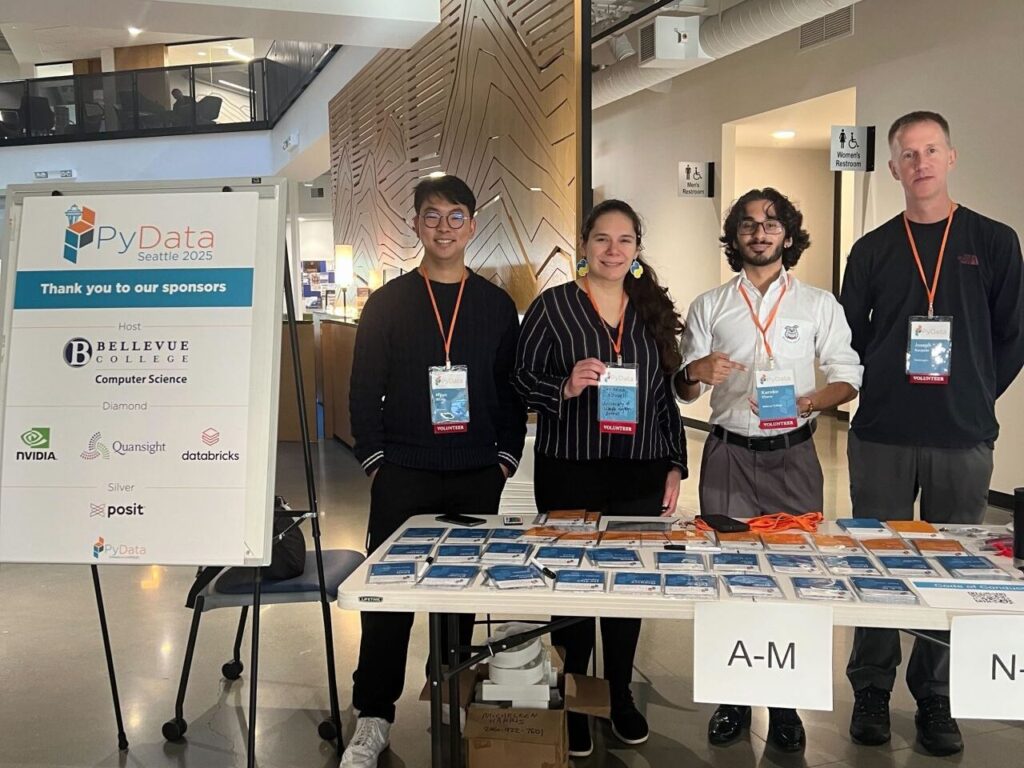 Four volunteers posing for a picture at the registration table for PyData Seattle 2025.