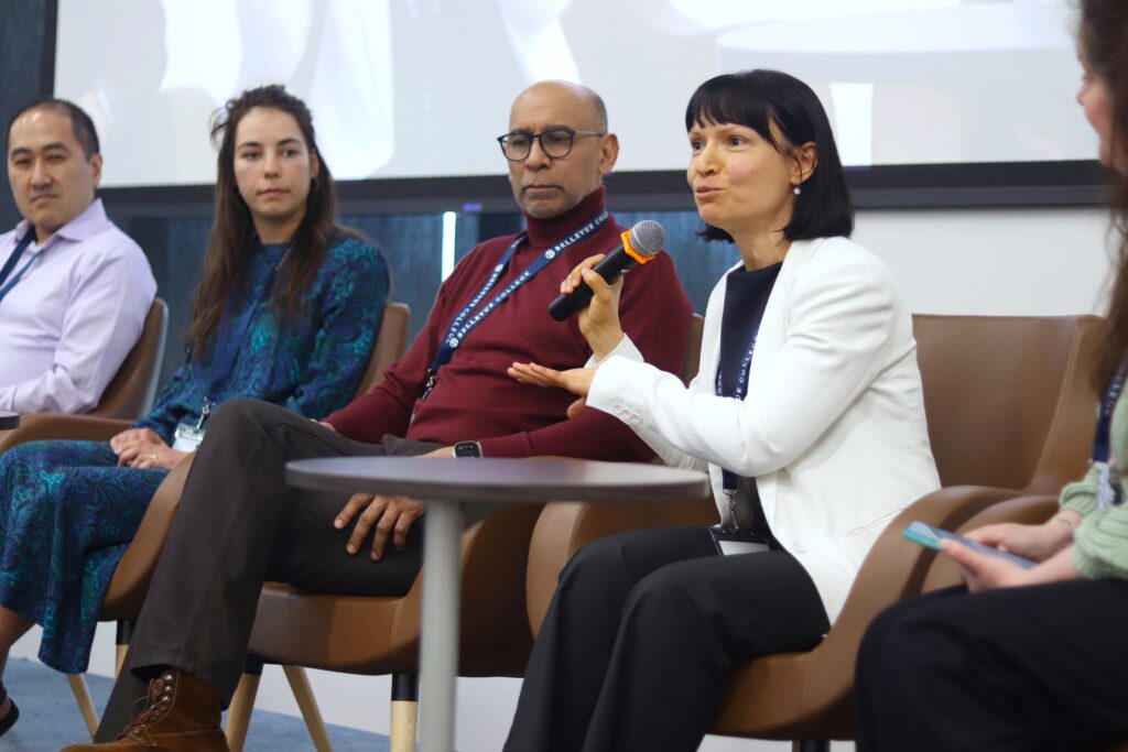 A panel of speakers with one holding and speaking into the mic.