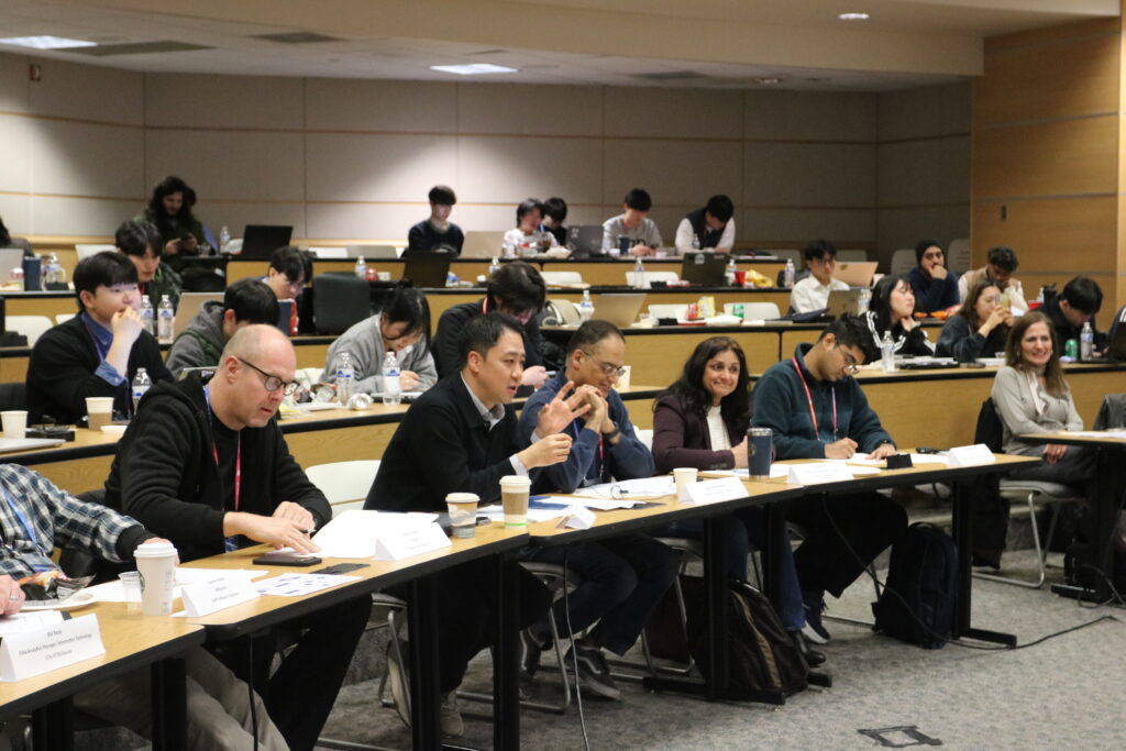 A panel of judges seated in the front row providing feedback on a student presentation