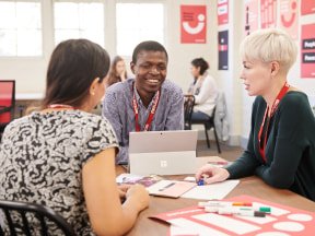 Two women and a man in a meeting representing working on an assignment