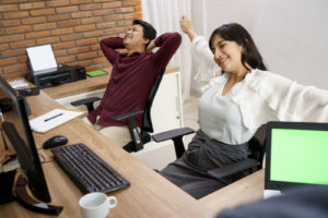 An attractive and cheerful coworker was lying down and smiling as he sat down. On his modern office desk