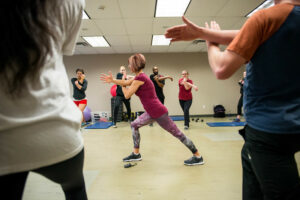 People in workout clothes standing in a circle stretching.