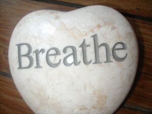 photo of heart shaped rock with the word breathe on it