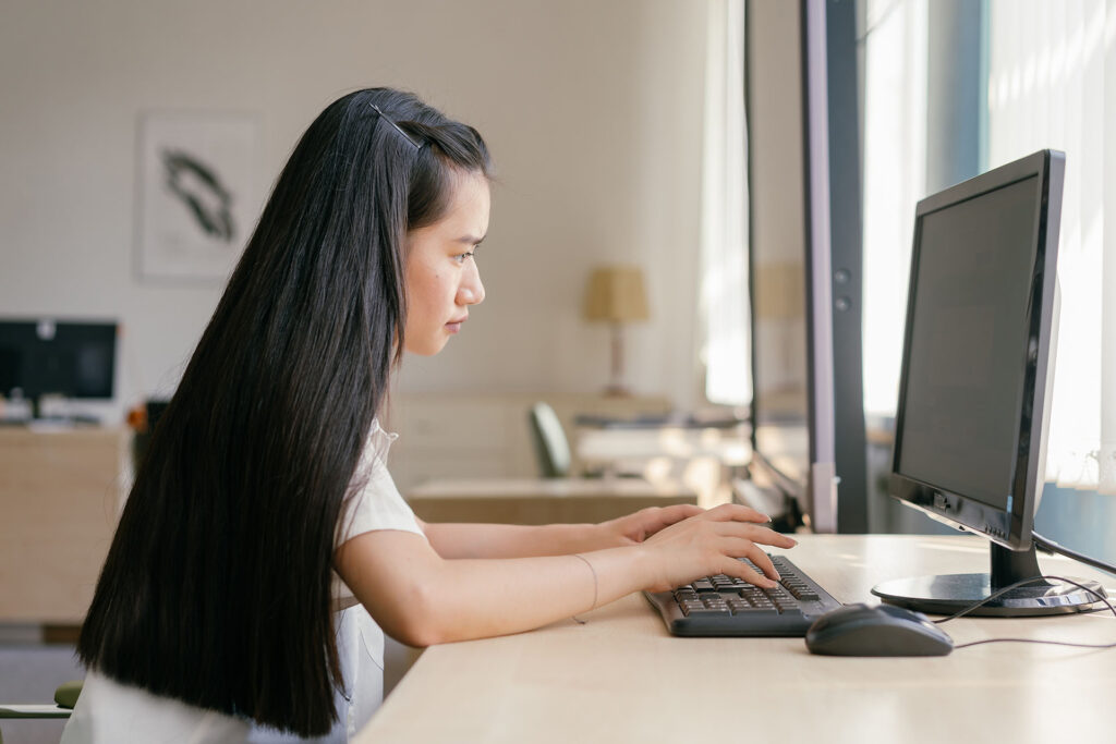 A student works on her computer by the window.