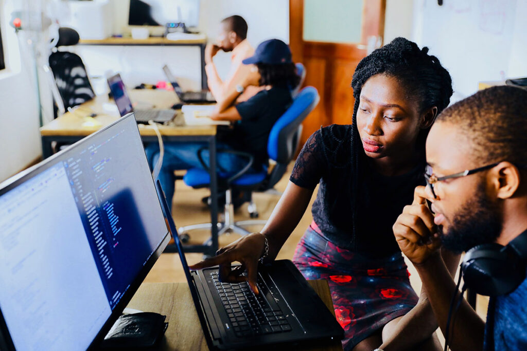 A student works with a professor at a computer.