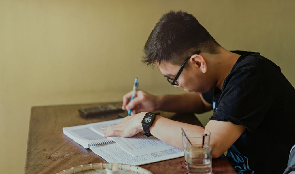 A student studies from books at a table.