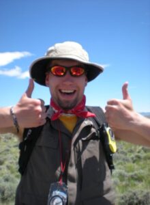 Nate Goodman giving two thumbs up out in the field at geology camp