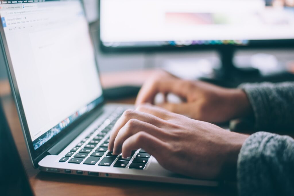 white hands on a laptop keyboard with screen illuminated and fingers are posed to type