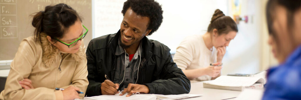 Two students working together. One is smiling at the other