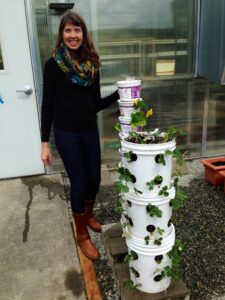 Karrin stands next to upright gardening buckets