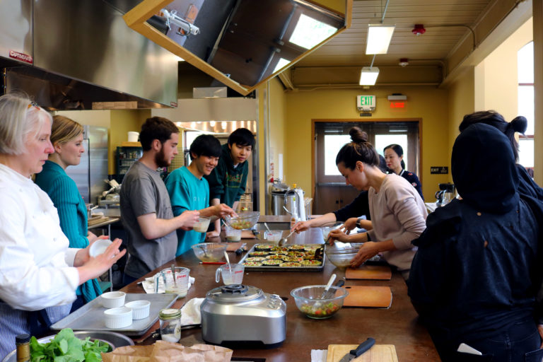 Students cooking organic food during a sustainability field trip to 21 Acres Farm