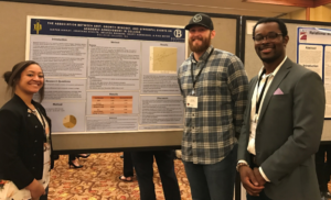 Three students in front of their poster