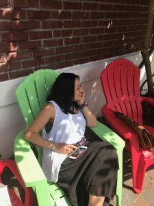 Donna Miguel sitting in the shade in a large green chair